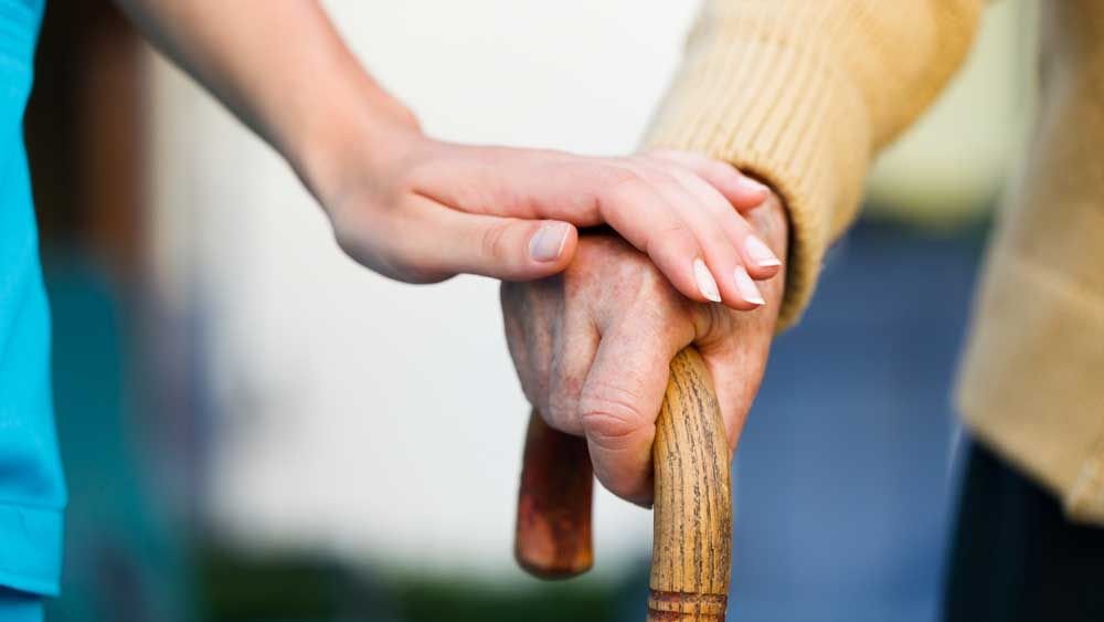 a carer holding an old mans hand
